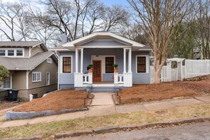 A two-story house with a front porch, a garage, and a fenced yard.