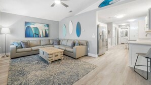 A modern living room with a sectional sofa, a coffee table, and a ceiling fan.