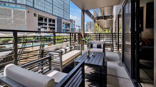 Un área de estar moderna al aire libre con piscina, una escalera y vistas a la ciudad.