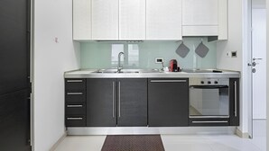 A modern kitchen with a stainless steel sink, a built-in oven, and a clock on the wall. - VISCONTI APARTMENT (Rome)