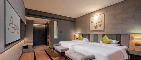 A modern hotel room with two beds, a bench, a wall-mounted TV, and a door leading to another room.