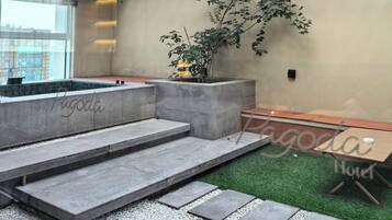 Um interior moderno com parede de concreto, pérgola de madeira e um pequeno jardim interno.