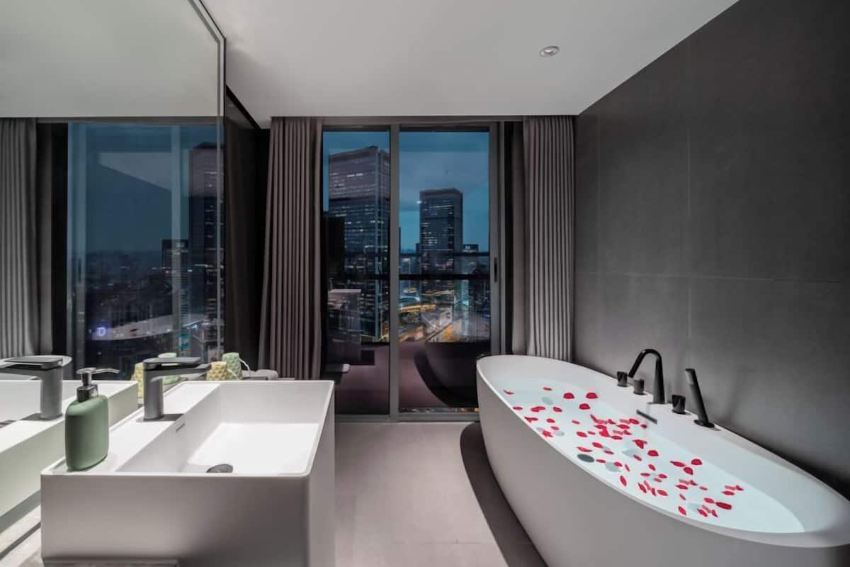A modern bathroom with a large bathtub, a separate shower area, and a vanity with a mirror.