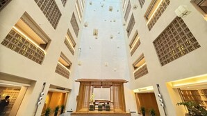 Un interior de hotel moderno con un atrio central, varios pisos y una zona de recepción en la planta baja.