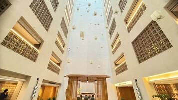 Un interior de hotel moderno con un atrio central, varios pisos y una zona de recepción en la planta baja.