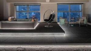 Una sala moderna con una zona de estar central, una piscina pequeña y grandes ventanales con vistas a la ciudad.