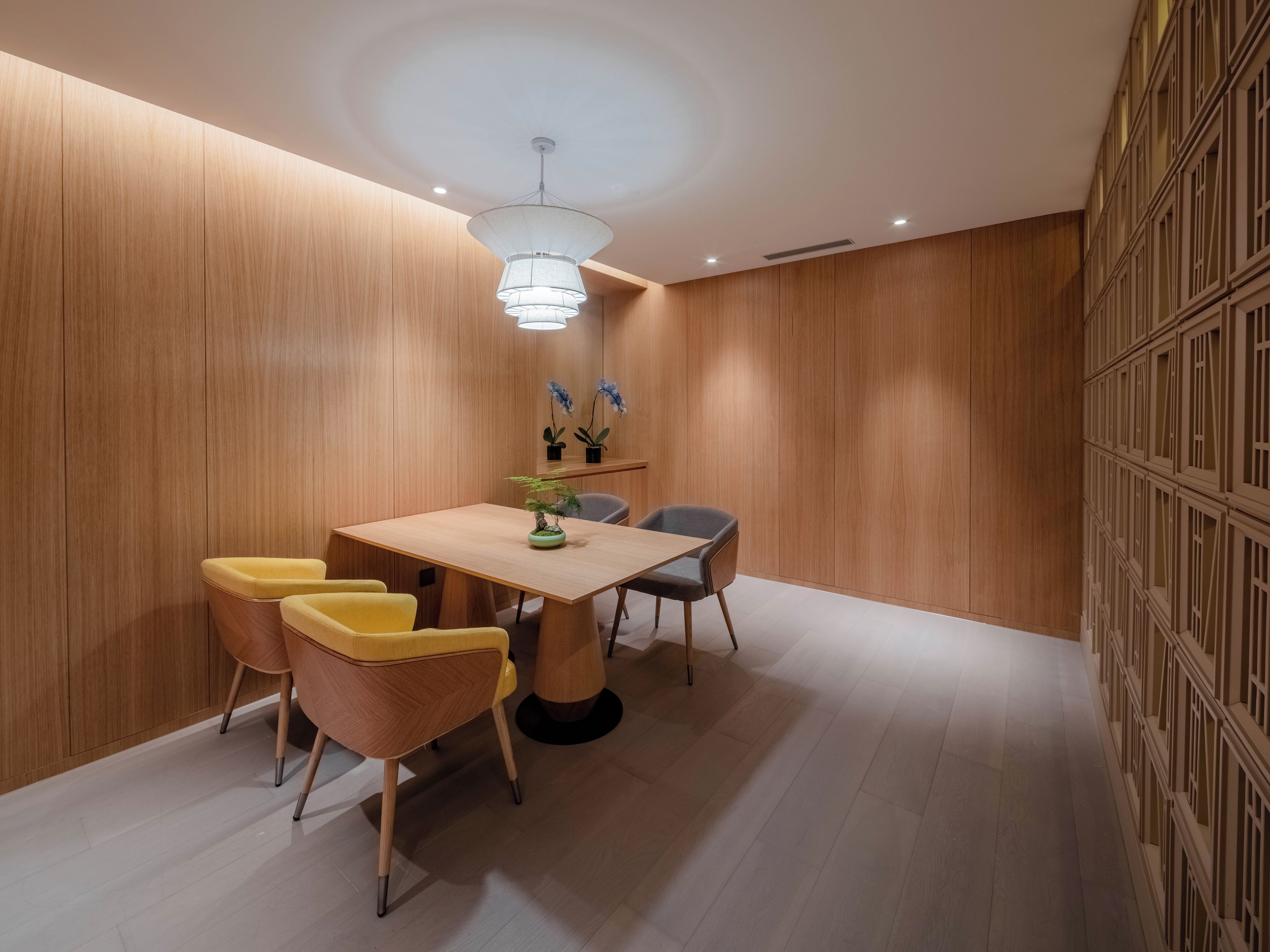 A modern dining area with a wooden table, chairs, and a hanging light fixture.