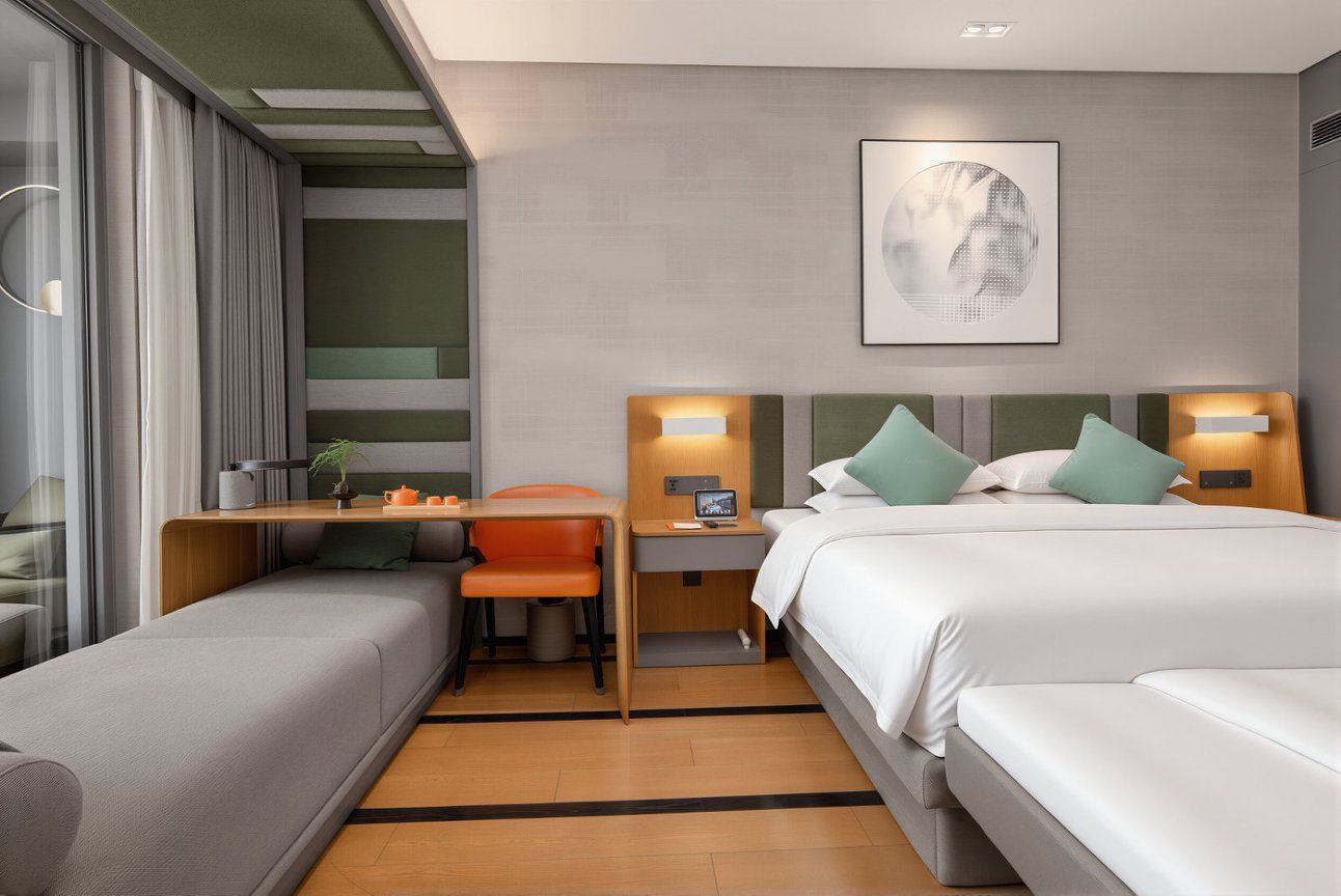 A modern hotel room with a bed, a desk, a chair, and a bedside table.