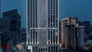 Un edificio de hotel alto con diseño moderno, caracterizado por líneas verticales y un letrero llamativo en la parte superior.