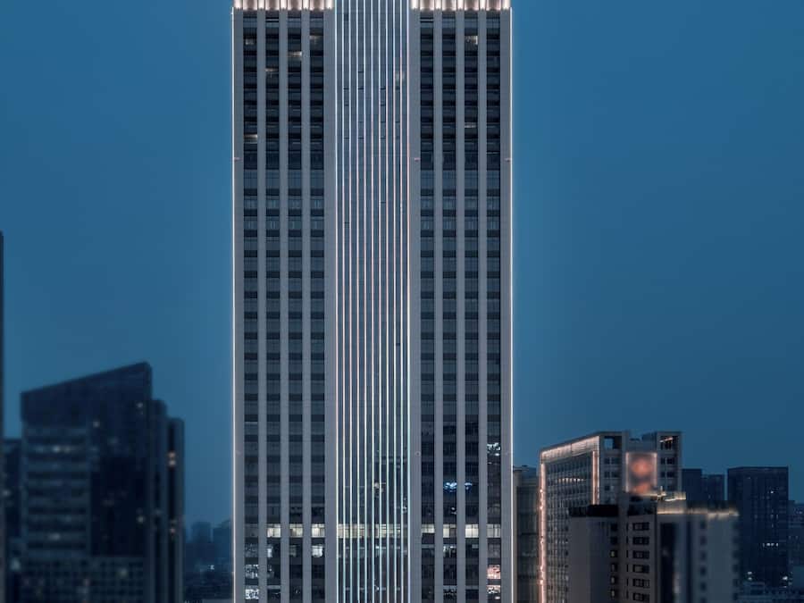 A tall hotel building with a modern design, featuring vertical lines and a prominent sign at the top.