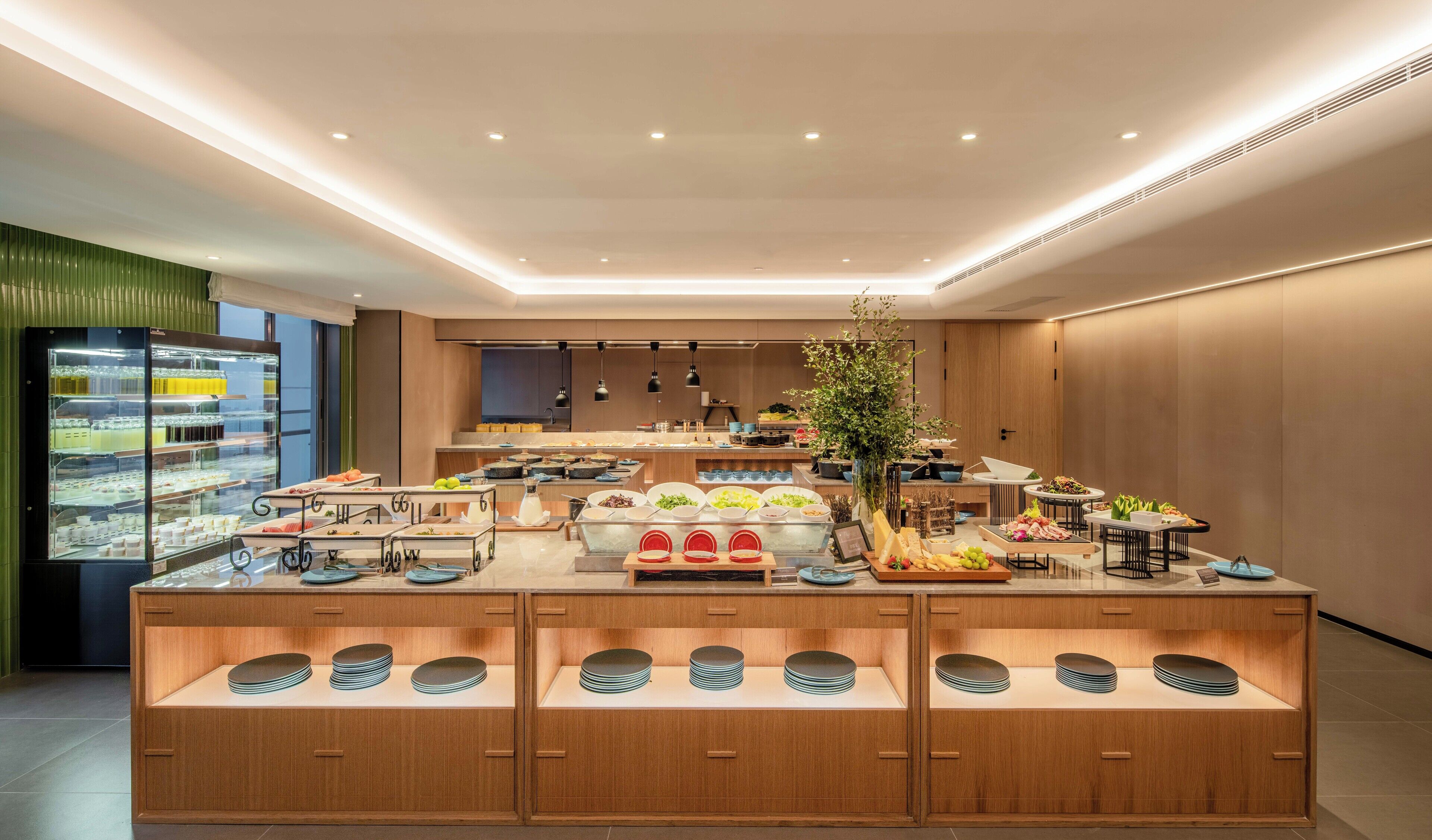 Un bufé de desayuno moderno con diversos alimentos y una vitrina de vidrio.