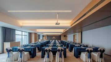 A conference room with multiple tables, chairs, and a projector.