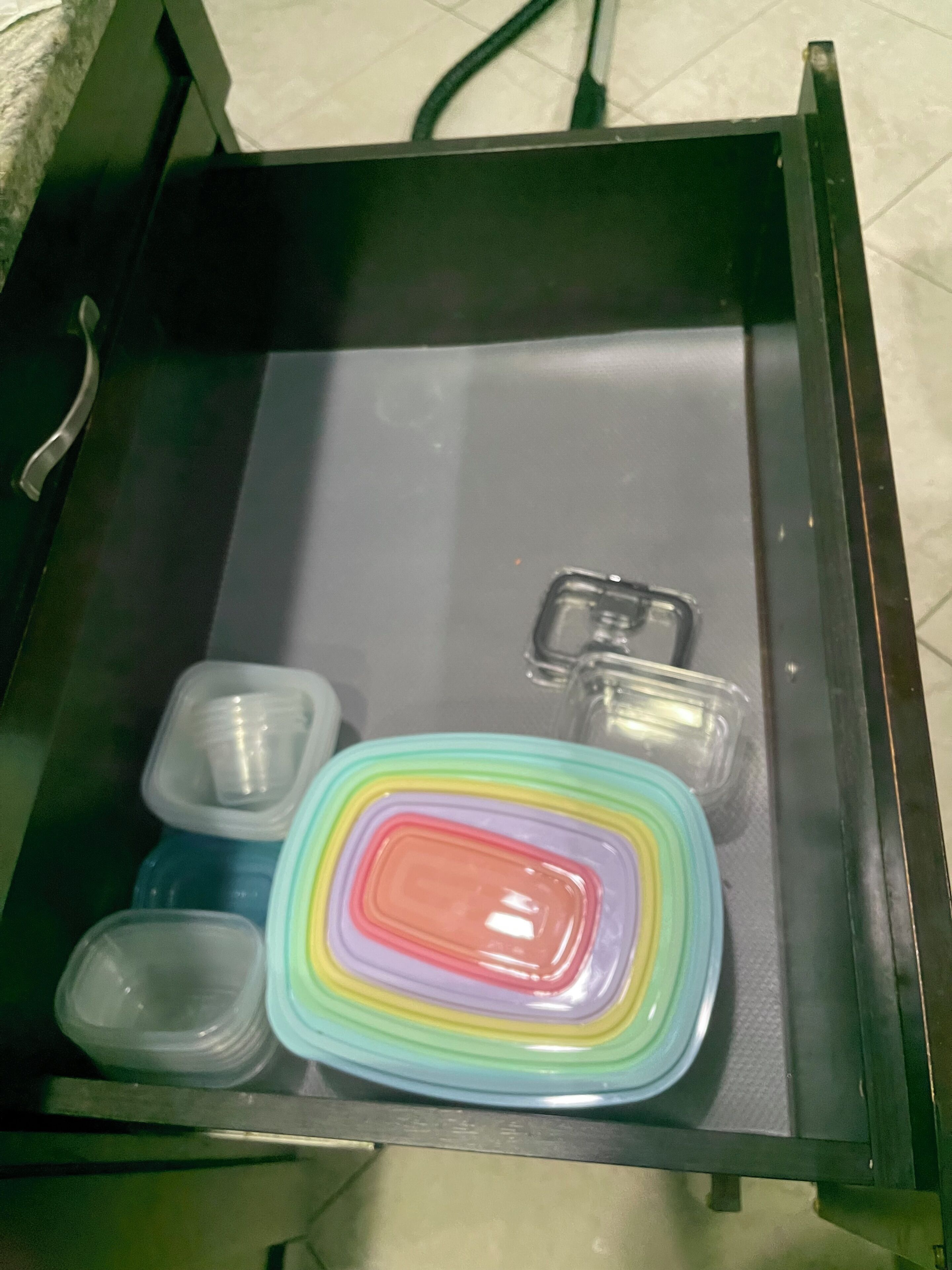 A drawer with various plastic containers and a colorful, multi-layered object.