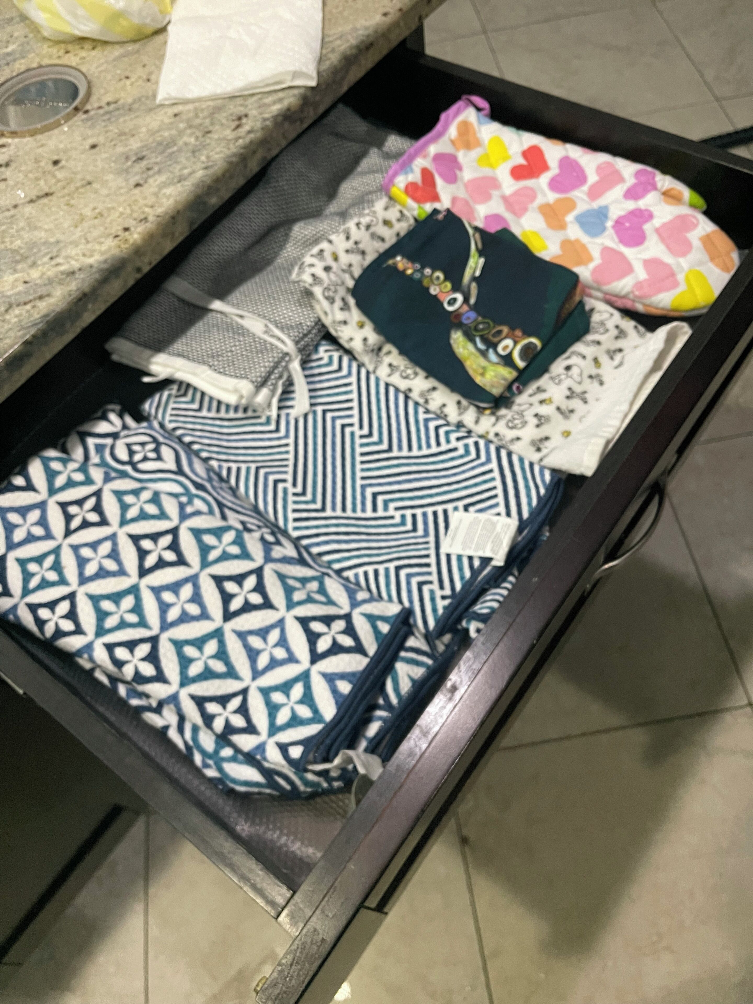 A suitcase with various items including a patterned bag, a white shirt, and a colorful heart-patterned pouch.