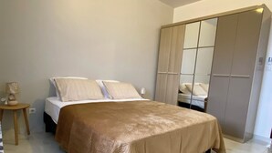 Ein Schlafzimmer mit Bett, Nachttisch, Lampe und Kleiderschrank.