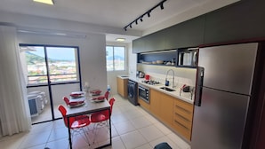 A modern kitchen with a dining area, large windows, and a view of the city.