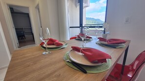 Ein Esstisch, gedeckt mit Tellern, Besteck und Weingläsern, mit Blick auf einen Berg durch ein Fenster.