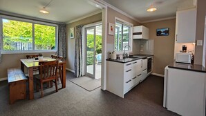 A compact kitchen with a dining area, a refrigerator, and a microwave. - Happy Days and Relaxing Stays (Te Anau)