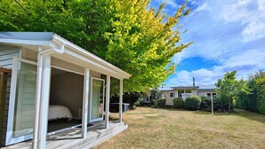 A single-story house with a covered porch and a bedroom visible through the open door. - Happy Days and Relaxing Stays (Te Anau)