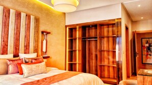 A spacious bedroom with a large bed, a wooden wardrobe, and a modern chandelier.