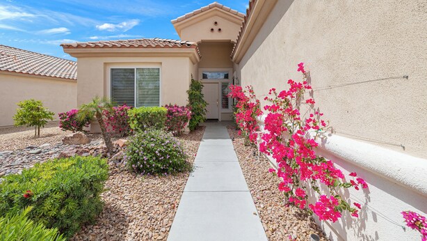 A residential property with a pathway leading to a door, surrounded by various plants and flowers. -  Sun City, Palm Desert, CA, Home in 55+ Community (Palm Desert)