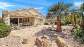 A house with a patio area, outdoor seating, and a palm tree. -  Sun City, Palm Desert, CA, Home in 55+ Community (Palm Desert)