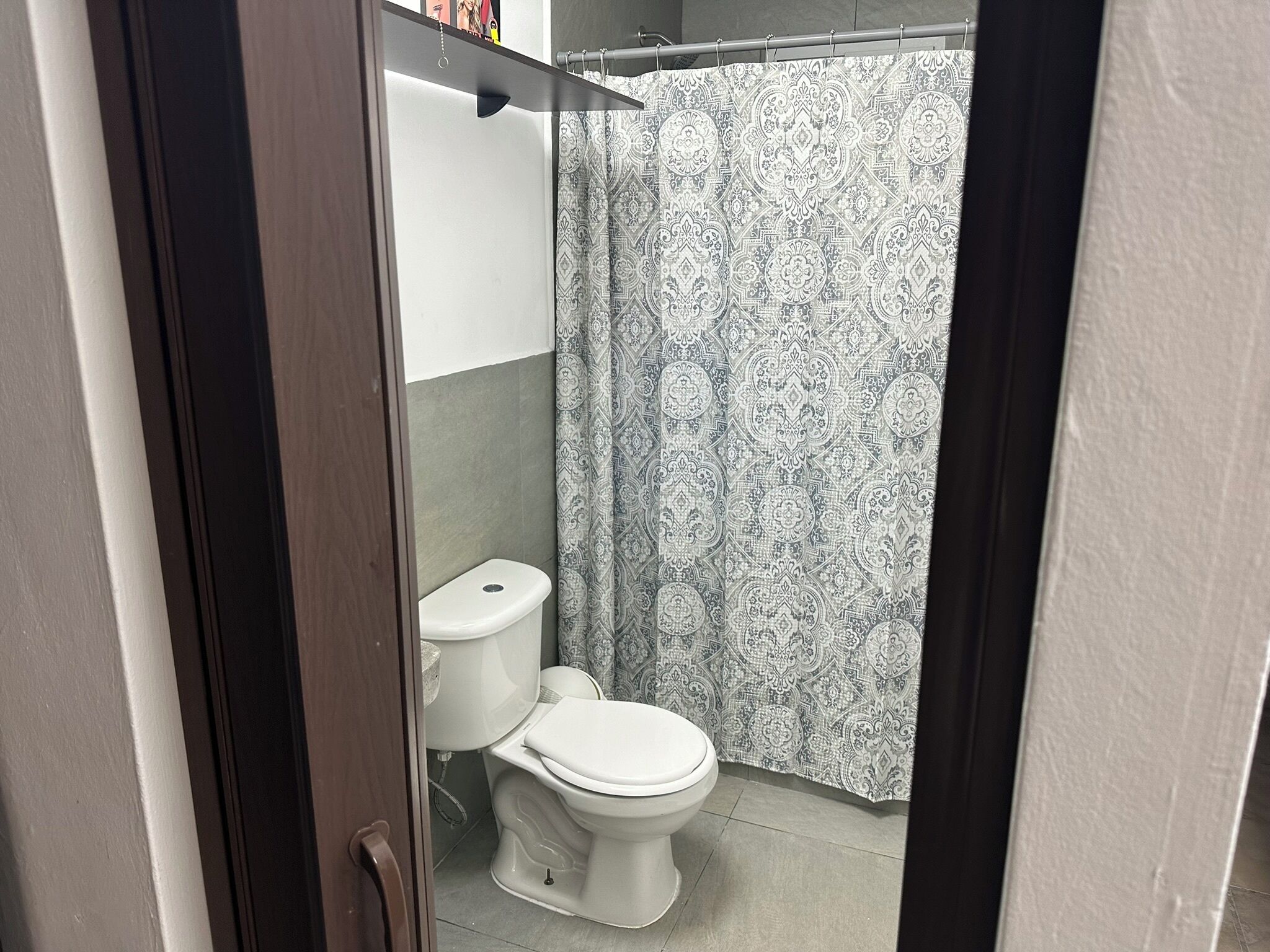 Ein Badezimmer mit Toilette, Duschvorhang und Handtuchhalter.