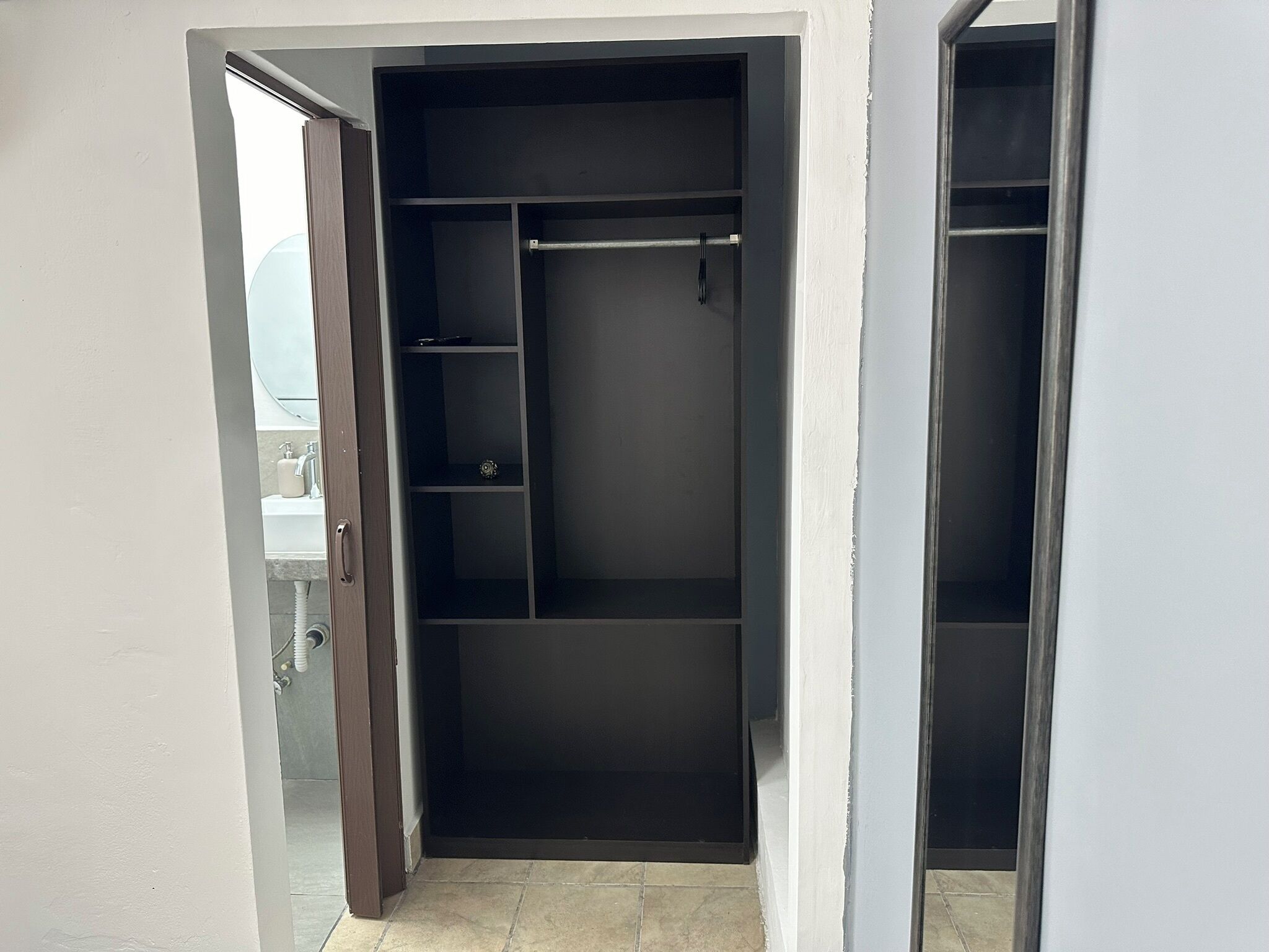A walk-in closet with open shelves and a hanging rod.