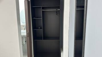 A walk-in closet with open shelves and a hanging rod.