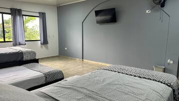 Habitación de hotel con dos camas individuales, un televisor de pantalla plana montado en la pared y un ventilador de techo.