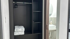 Un vestidor con barra para colgar, estantes y un pequeño banco.