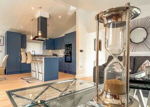 Une cuisine moderne avec des meubles bleus, un îlot central et un coin repas doté d’une table en verre.