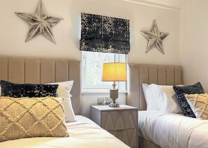 A hotel room with two beds, star decorations, a window with a lamp, and a nightstand. - 3 bedroom accommodation in Chipping (Chipping)