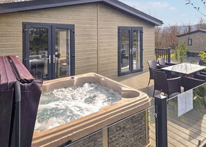 A hot tub on a deck with outdoor furniture and sliding glass doors. - 1 bedroom accommodation in Chipping (Chipping)