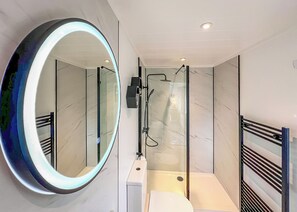 A modern bathroom with a large mirror, a shower, and a toilet. - 1 bedroom accommodation in Chipping (Chipping)