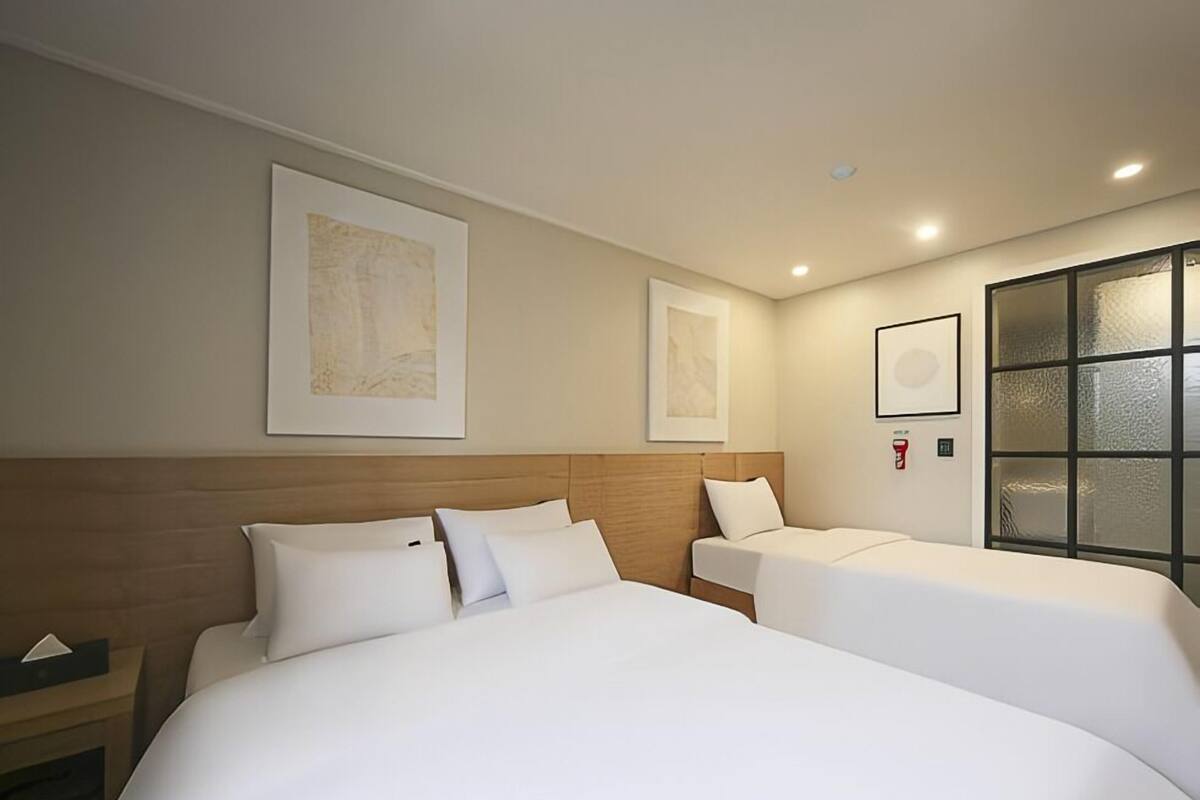 A hotel room with two beds, a wooden headboard, and framed artwork on the walls.
