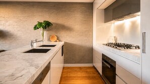 Una cucina moderna con un piano di lavoro in marmo, un lavello, un fornello e un pavimento in legno.