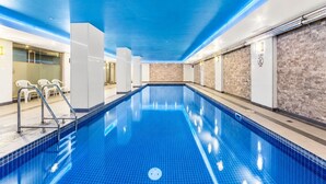 Een binnenzwembad met helderblauw water, omringd door witte muren en een blauw plafond.