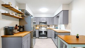 Eine moderne Küche mit grauen Schränken, Holz Arbeitsplatten und eingebauten Geräten.