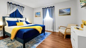 Ein Schlafzimmer mit einem Bett, einem Schreibtisch, einem Stuhl und zwei Bildern an der Wand.