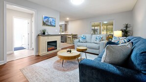 Ein modernes Wohnzimmer mit Kamin, einer Sofagarnitur und einem Essbereich.