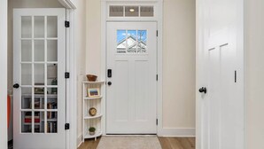 Un couloir avec une porte blanche, une porte en verre dotée d’étagères et un tapis sur le sol.