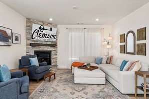 A living room with a stone fireplace, a sofa set, a coffee table, and a rug.