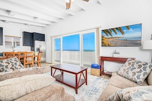 Ein Wohnzimmer mit einer Couch, einem Couchtisch und einem Bild von einem Strand.