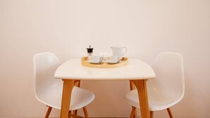 A table with a tray holding a coffee maker, cups, and a teapot.