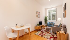 A modern living room with a dining area, a sofa, a TV, and a large window.