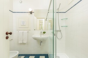 A bathroom with a white sink, a glass shower enclosure, and a blue and white tiled floor. - Urban apartment with Balcony in Porto (Oporto)