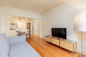 A modern living room with a sofa, TV, and a small dining area with chairs and a table. - Urban apartment with Balcony in Porto (Oporto)