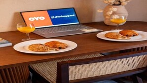 A laptop with the OYO logo, a glass of orange juice, and two plates of croissants on a wooden table. - Appartement moderne - AC-1BR-4P- Genève (Genève)