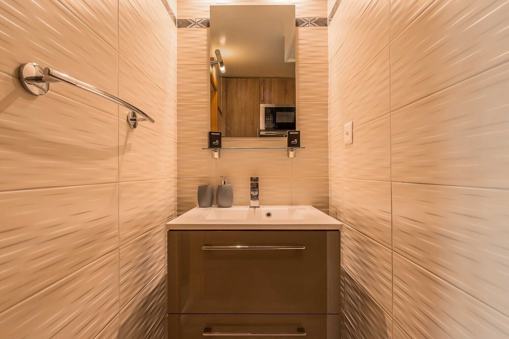 Un baño moderno con un espejo grande, un lavamanos y un perchero para toallas.